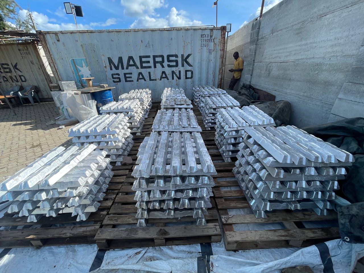 Aluminium ingot palletised for export beside a shipping container